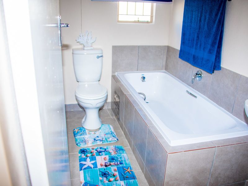A functional bathroom featuring a bathtub with tiled surround, a standard toilet, and a wall-mounted basin.