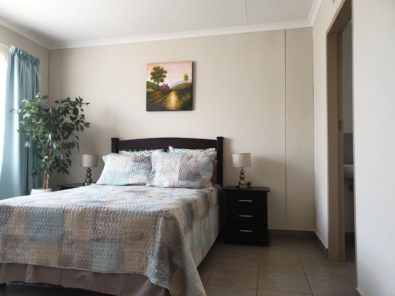 A functional bedroom featuring tiled flooring, neutral wall finishes, and direct access to an adjoining room.