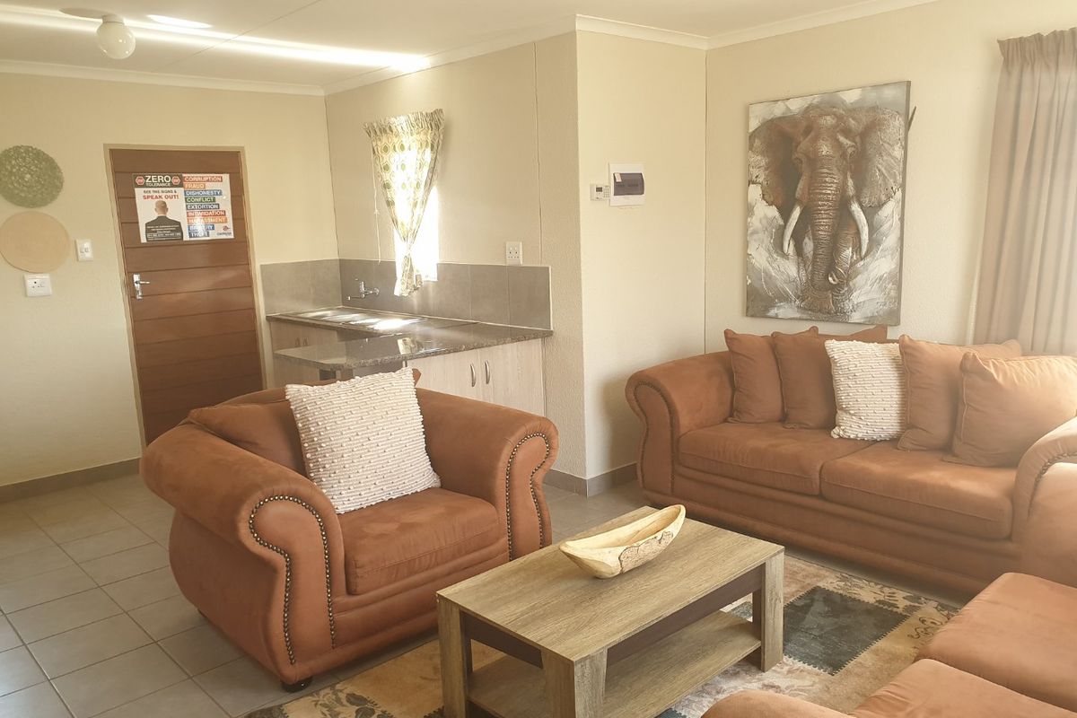 Open-plan living area featuring tiled flooring and a compact kitchen corner with built-in cabinetry and sink.