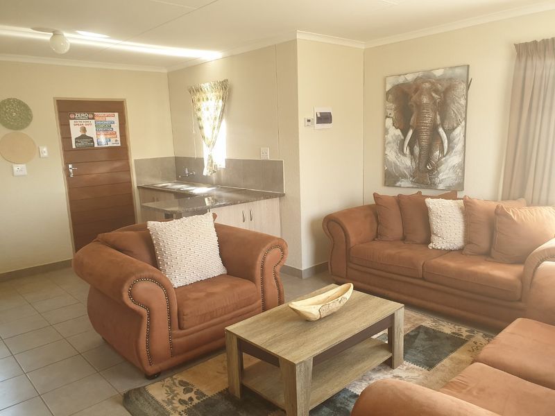 Open-plan living area featuring tiled flooring and a compact kitchen corner with built-in cabinetry and sink.