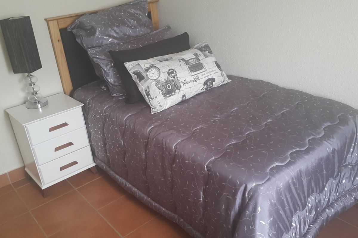 A compact bedroom featuring tiled flooring and neutral wall finishes, providing a functional space for a single bed setup.