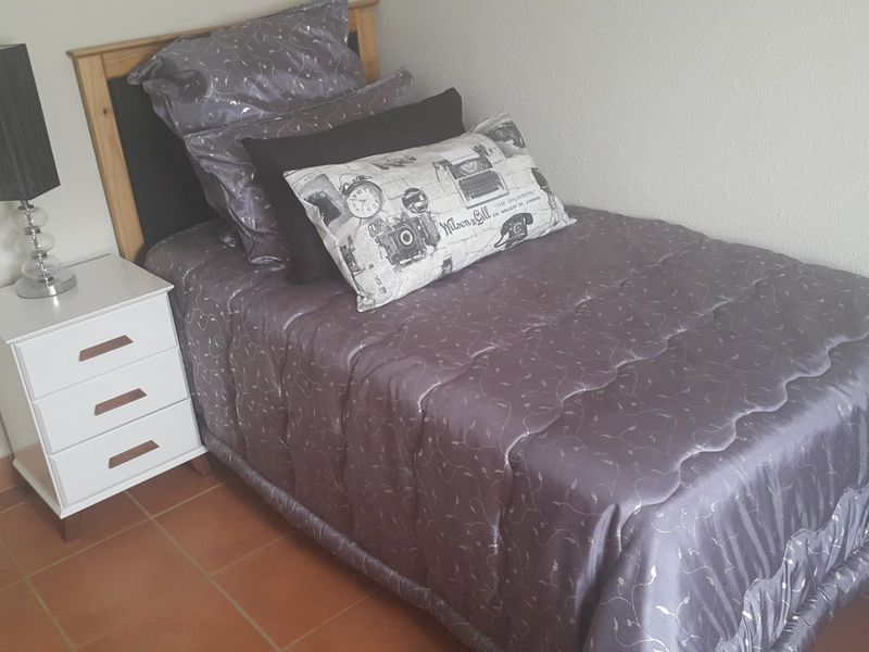 A compact bedroom featuring tiled flooring and neutral wall finishes, providing a functional space for a single bed setup.