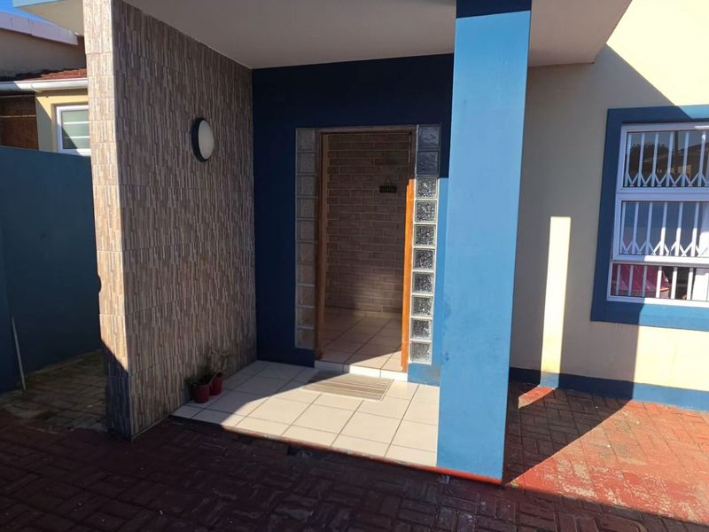 Front entrance area featuring a tiled porch, glass block accents, and security-fitted windows, leading into the main residence.