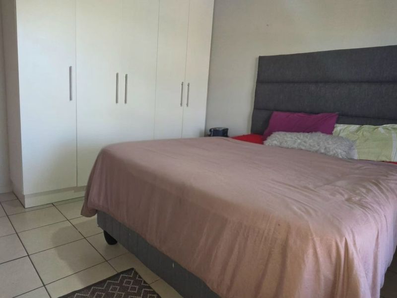 A bedroom featuring built-in cupboards and tiled flooring, with a view into an adjacent hallway.