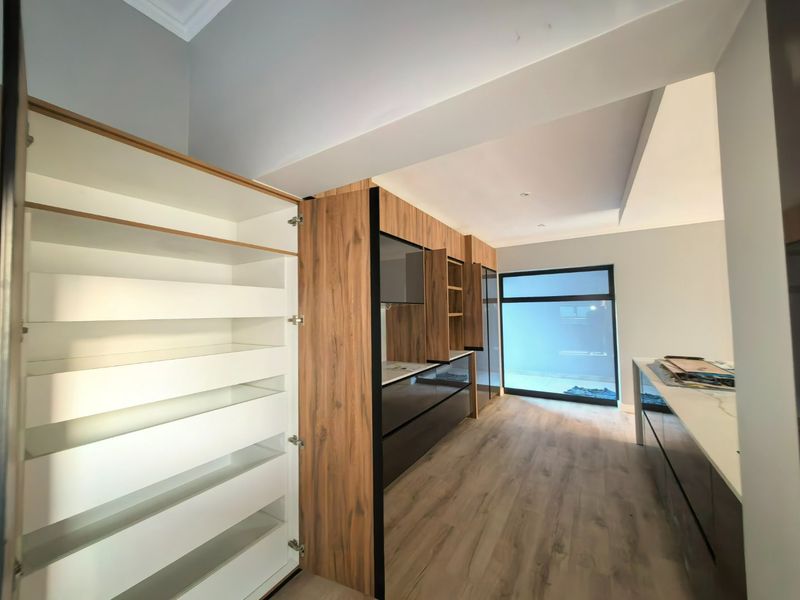 Modern kitchen featuring sleek wood-grain and dark cabinetry, stone countertops, and light laminate flooring, offering a clean and contemporary aesthetic.