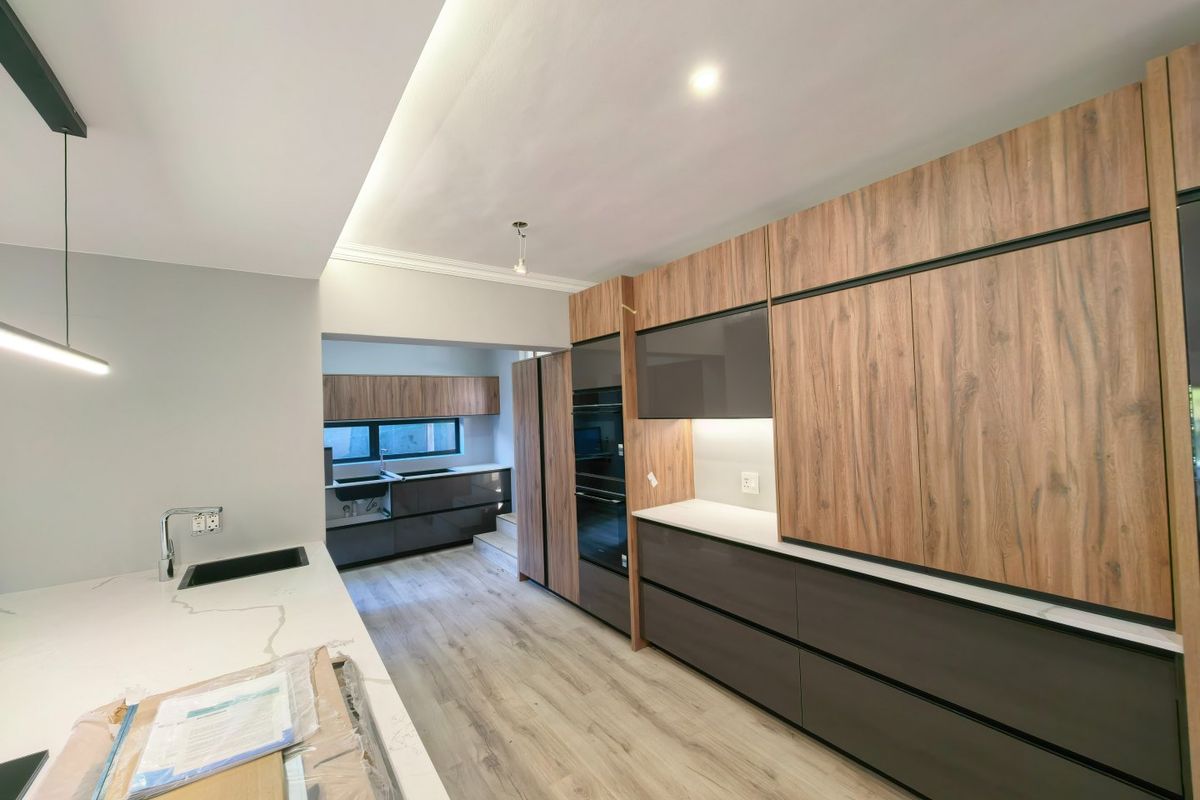 Modern kitchen featuring sleek wood-grain and dark cabinetry, stone countertops, integrated appliances, and recessed lighting in a clean, contemporary design.