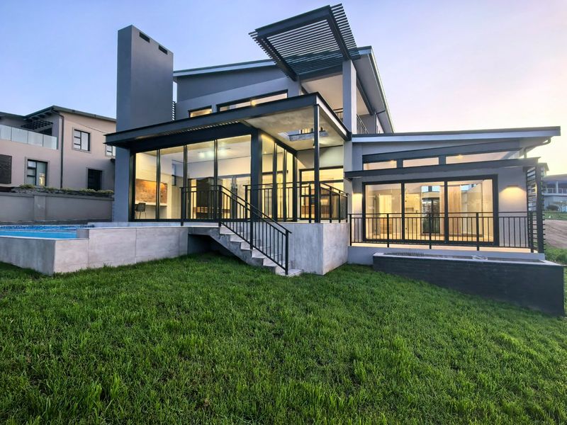 Modern rear exterior view featuring a swimming pool, covered patio with metal balustrades, and large glass sliding doors leading into the home.