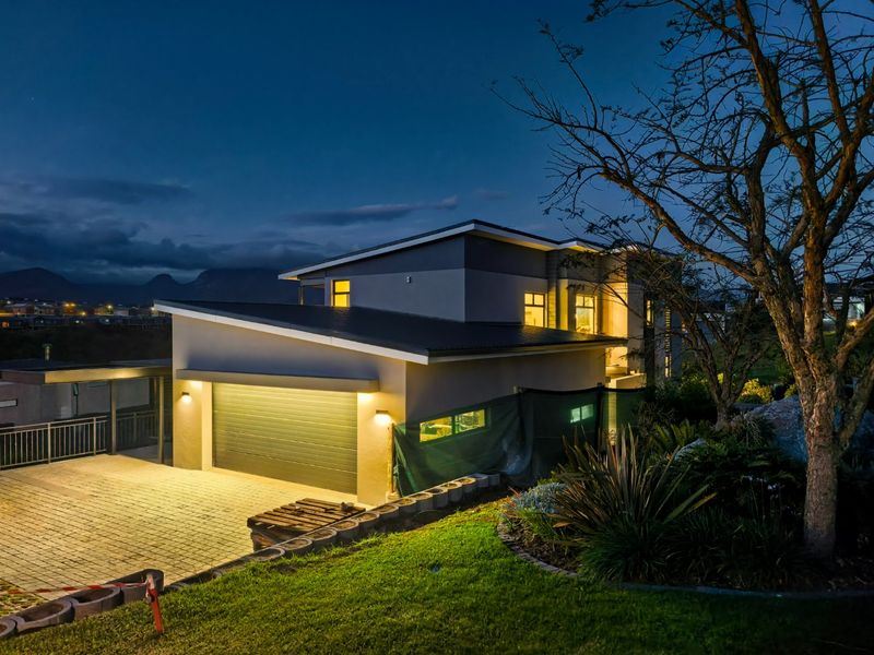 Modern double-story residential property at dusk, featuring a paved driveway, integrated garage, and landscaped garden area.