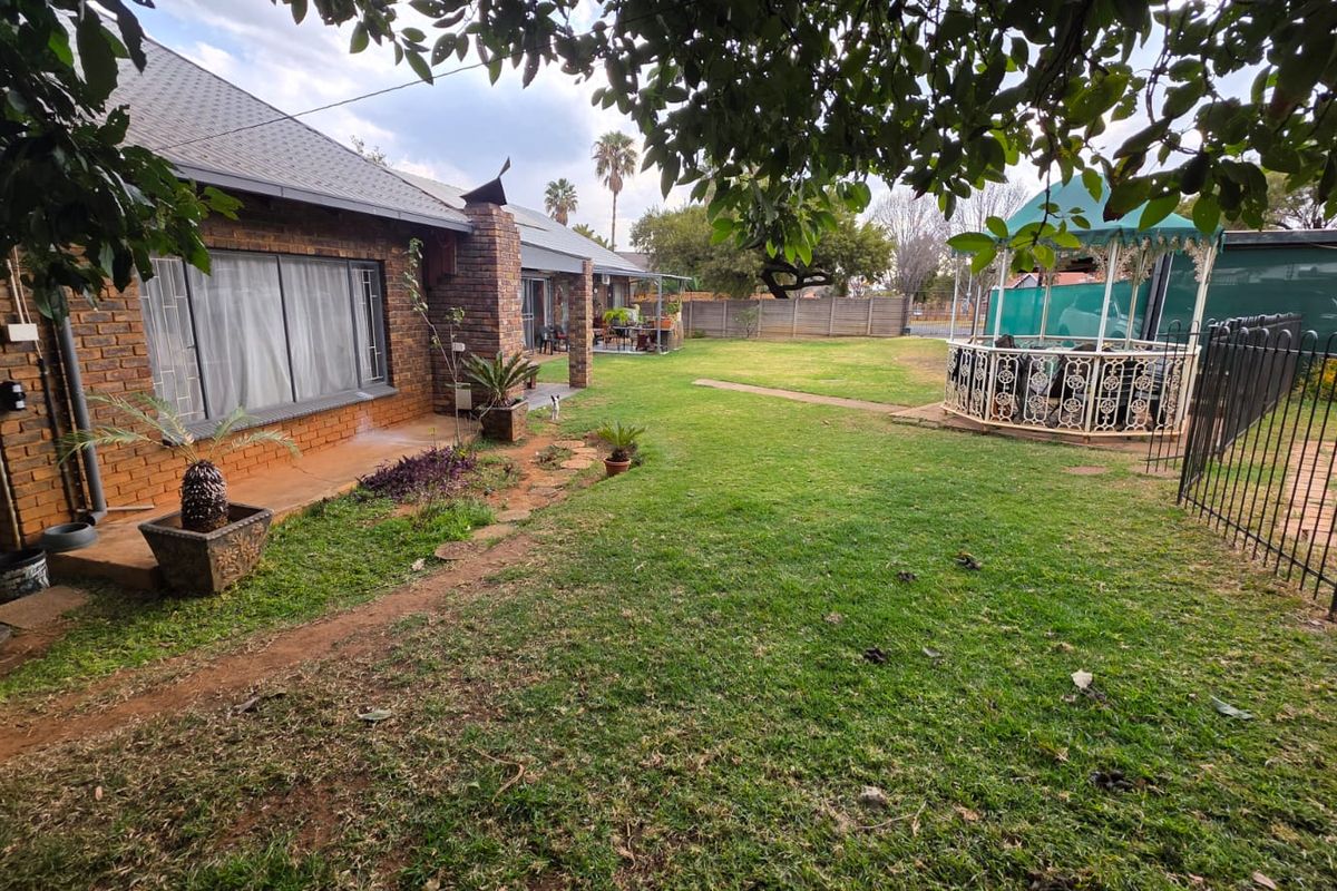 Spacious rear garden featuring a brick-built house, concrete patio area, and secure perimeter fencing, offering a private outdoor space.