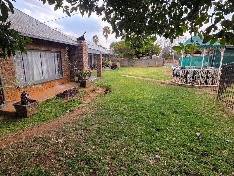 Spacious rear garden featuring a brick-built house, concrete patio area, and secure perimeter fencing, offering a private outdoor space.
