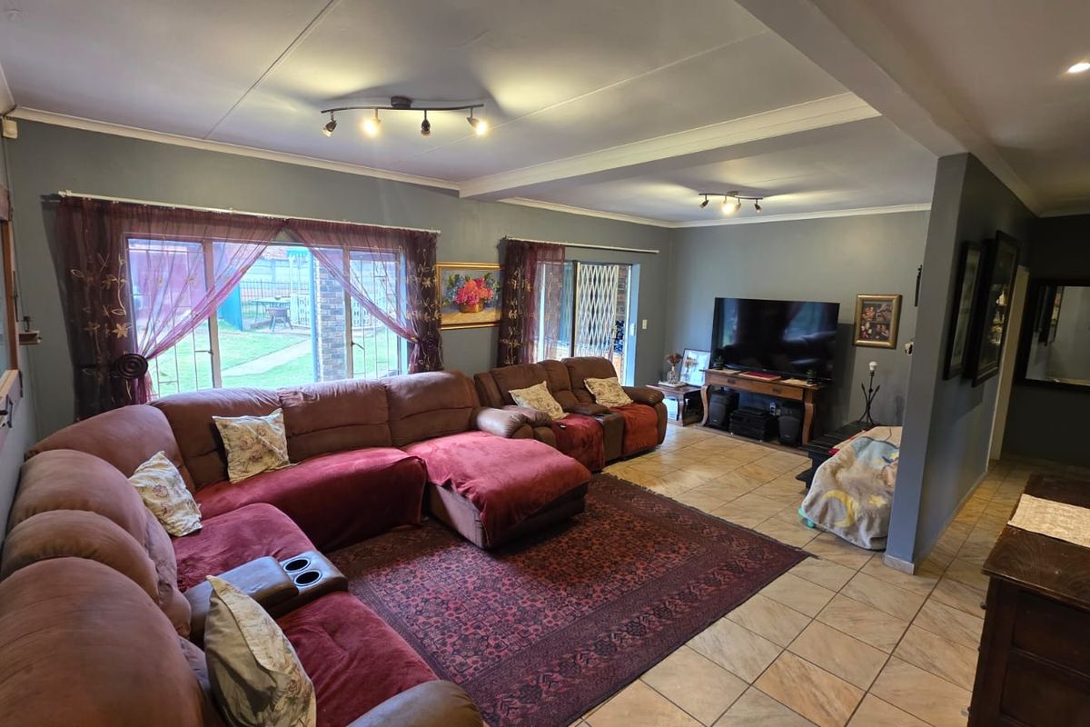 Spacious living room featuring tiled flooring, track lighting, and large sliding glass doors providing access to the rear garden area.