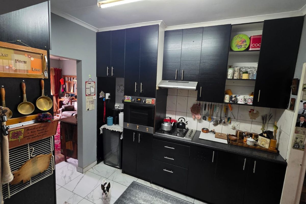 A functional kitchen featuring dark built-in cabinetry, a built-in oven, gas hob, extractor fan, and tiled flooring with a tiled backsplash.