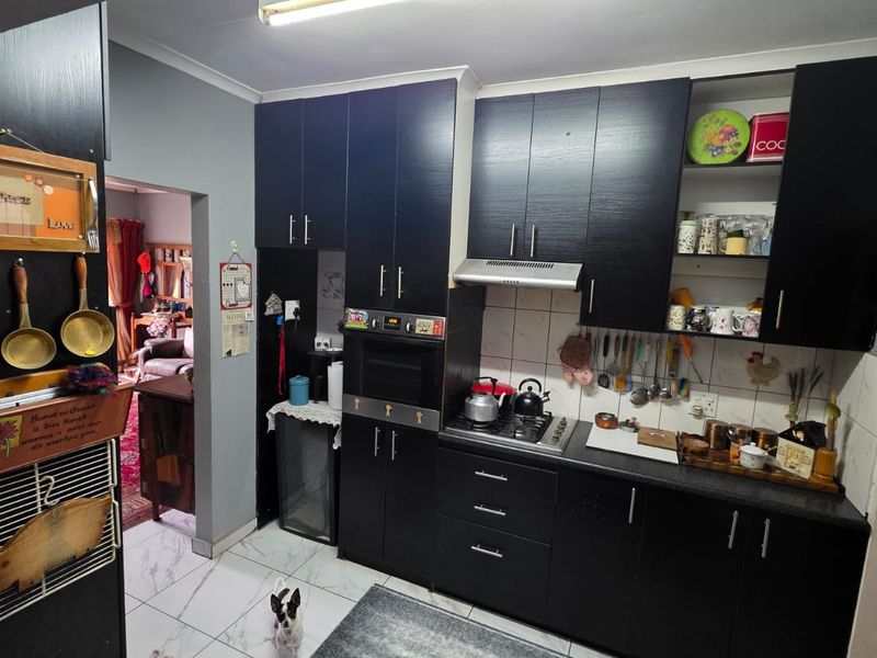 A functional kitchen featuring dark built-in cabinetry, a built-in oven, gas hob, extractor fan, and tiled flooring with a tiled backsplash.