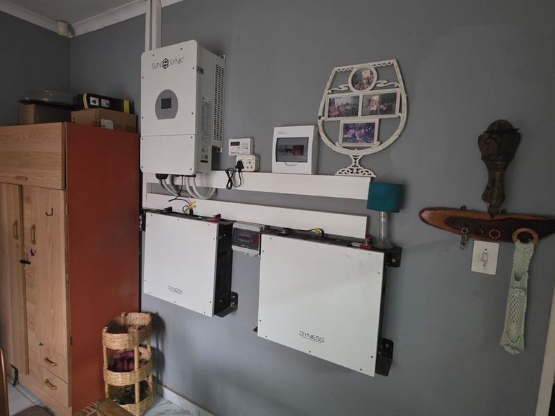 Utility area featuring a wall-mounted solar inverter and dual battery storage system for off-grid power management.