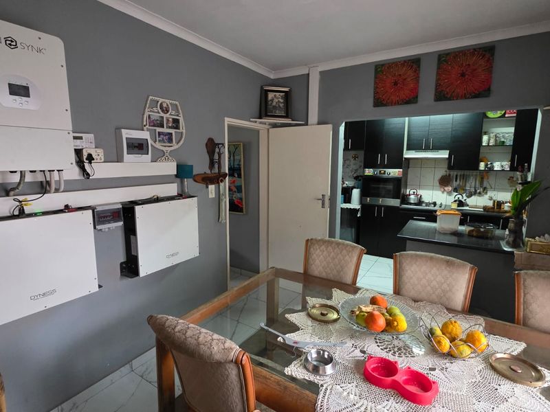 Open plan dining area featuring integrated solar power infrastructure and a view into the adjacent kitchen with dark cabinetry.