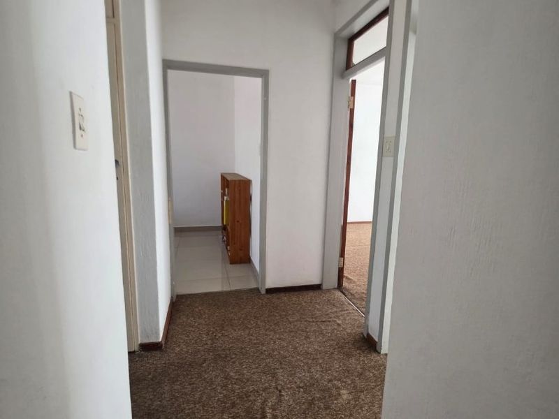 A functional hallway connecting multiple rooms, featuring carpeted flooring and neutral wall finishes, providing access to the rest of the townhouse.