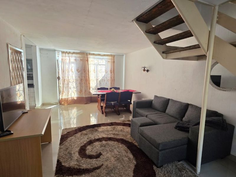 Open-plan living and dining area featuring tiled flooring and an internal staircase leading to the upper level.
