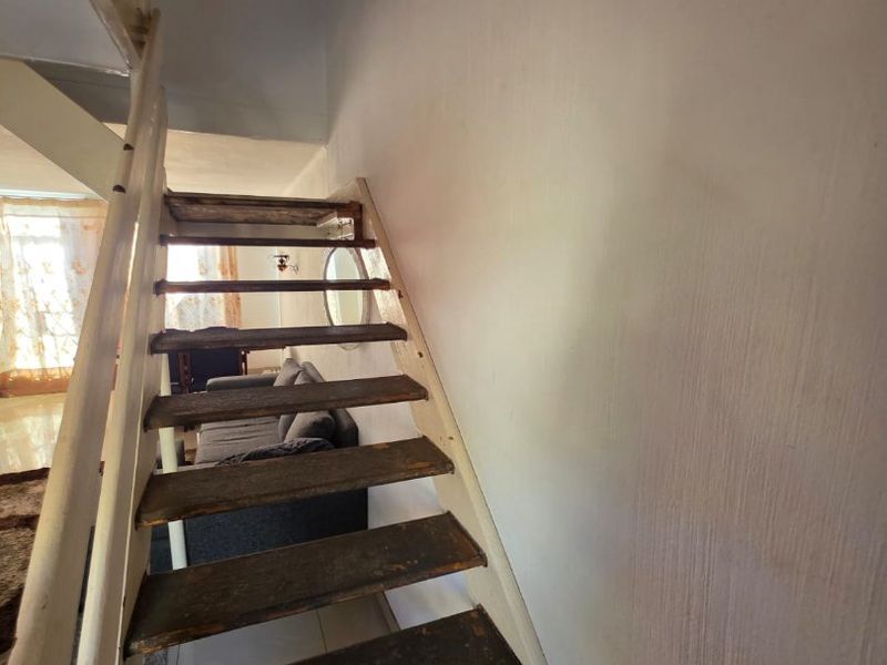 A staircase with worn wooden treads and a painted frame, showing signs of significant wear and tear in need of refurbishment.
