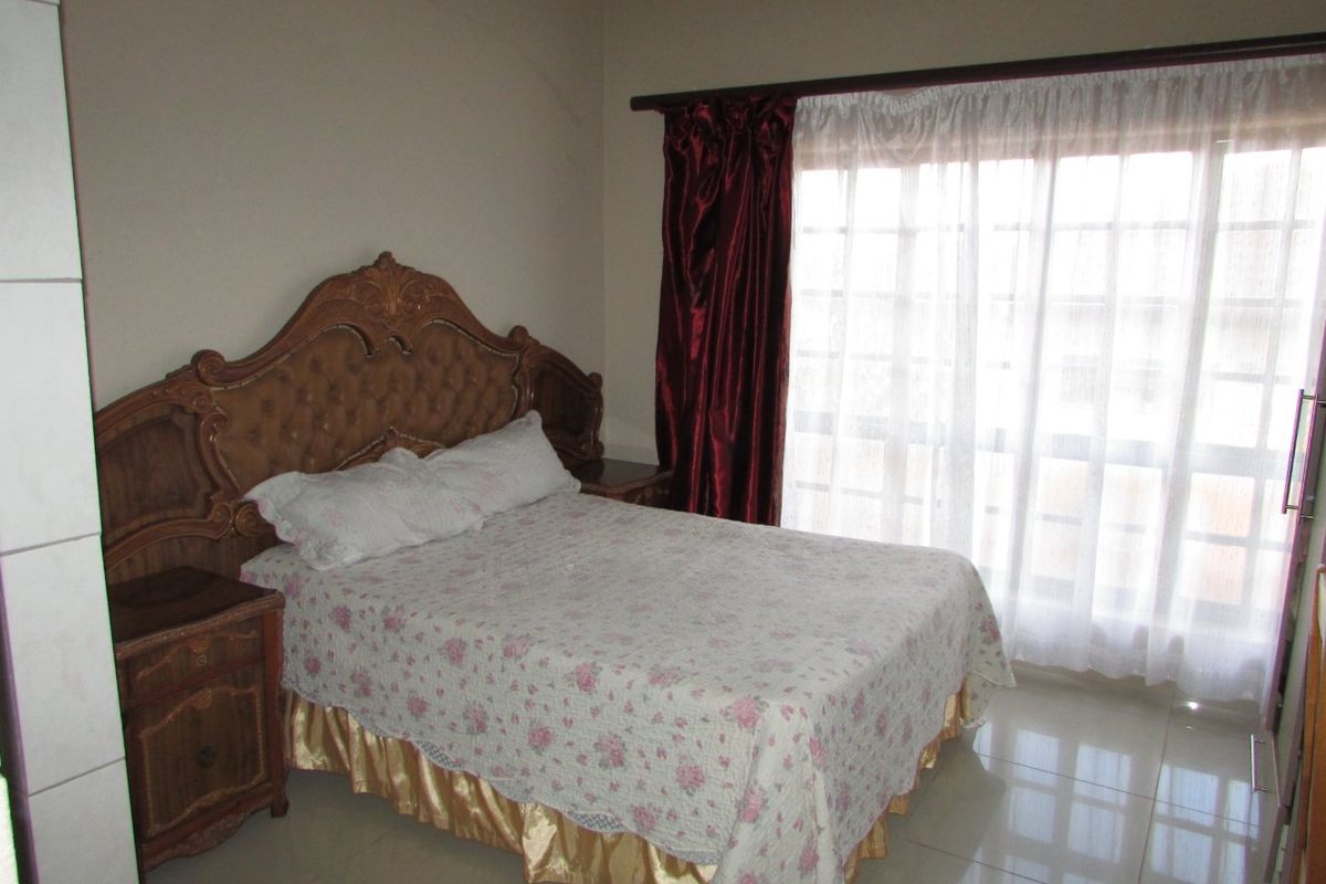 A bedroom featuring tiled flooring and a large window with curtain rod, providing natural light.