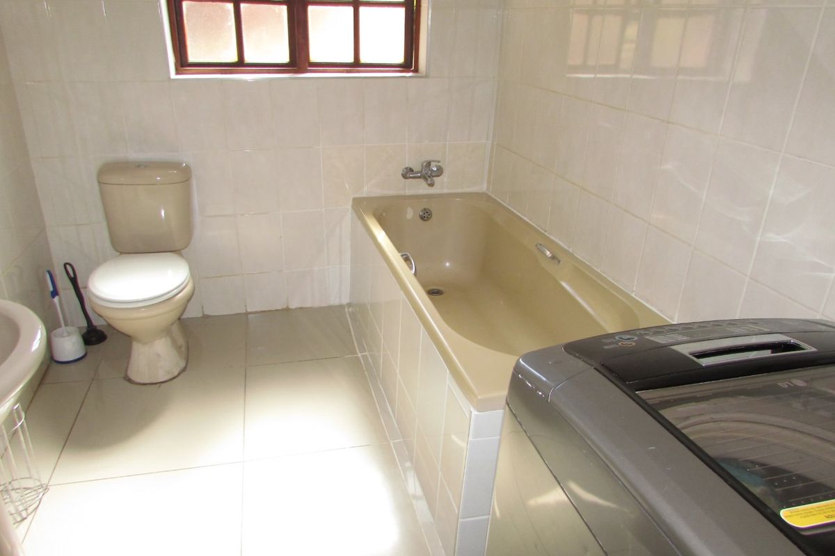 A functional bathroom featuring a bathtub, toilet, and tiled finishes, offering potential for modernization and aesthetic updates.