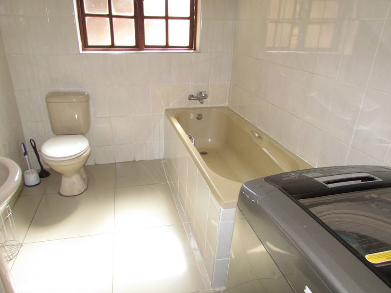 A functional bathroom featuring a bathtub, toilet, and tiled finishes, offering potential for modernization and aesthetic updates.