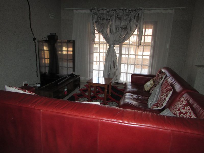A living room featuring textured walls and french doors leading to the exterior. The space requires cosmetic updates and improved lighting.