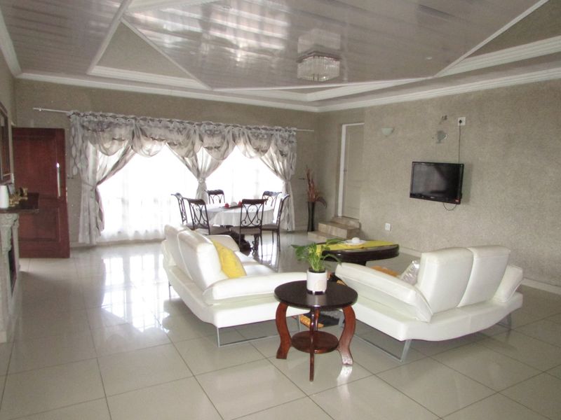 Spacious open-plan living and dining area featuring tiled flooring, a decorative coffered ceiling, and neutral wall finishes.
