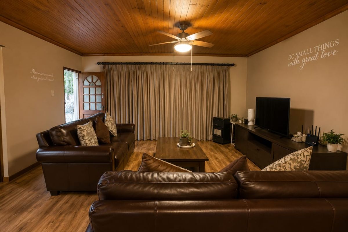 A cozy living room featuring warm timber ceiling paneling, a ceiling fan, and durable laminate flooring, creating a comfortable and inviting atmosphere.