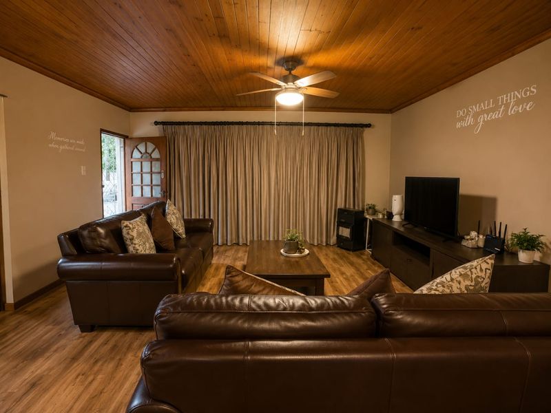 A cozy living room featuring warm timber ceiling paneling, a ceiling fan, and durable laminate flooring, creating a comfortable and inviting atmosphere.