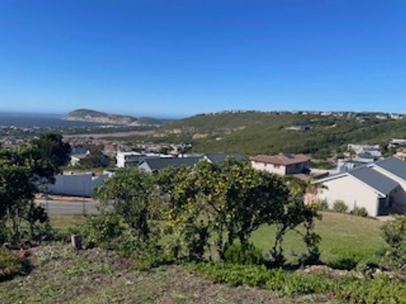 An elevated view overlooking a residential neighborhood with coastal hills and landscape in the background.