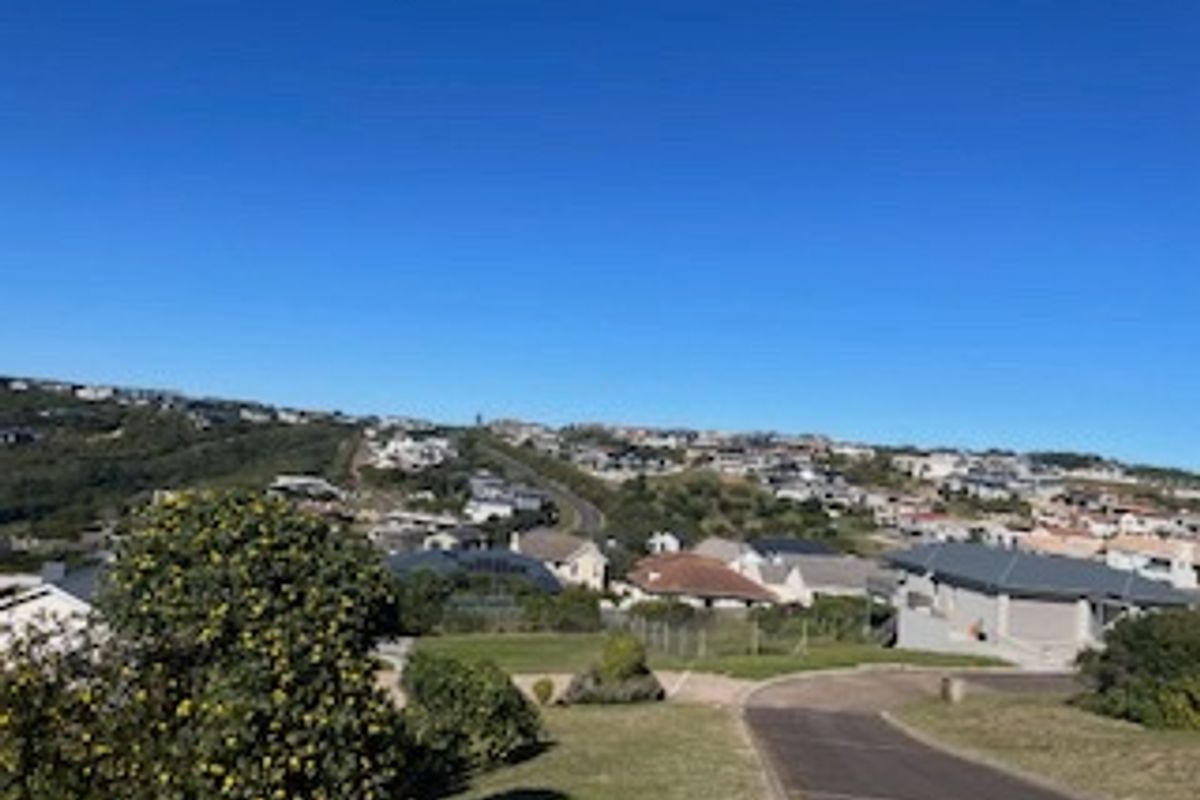 An elevated view overlooking a residential neighborhood with a paved driveway leading into the property.