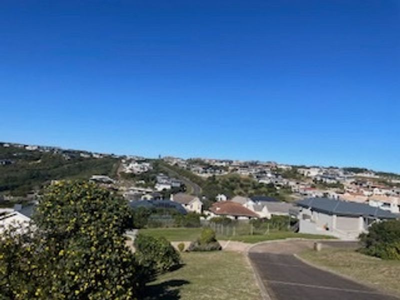 An elevated view overlooking a residential neighborhood with a paved driveway leading into the property.