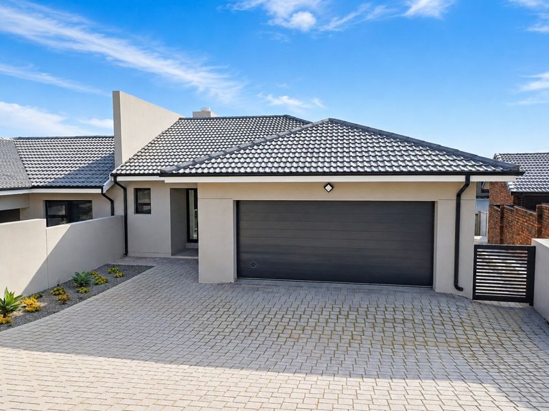 Modern front elevation featuring a paved driveway, automated garage door, and clean architectural lines with a tiled roof.