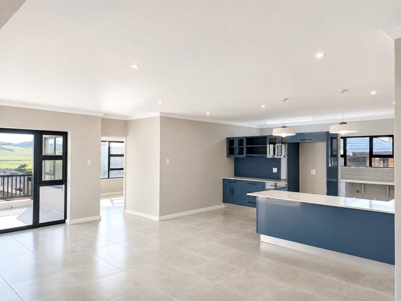 Spacious open-plan kitchen and living area featuring modern blue cabinetry, stone countertops, tiled floors, and large sliding doors leading to a balcony.