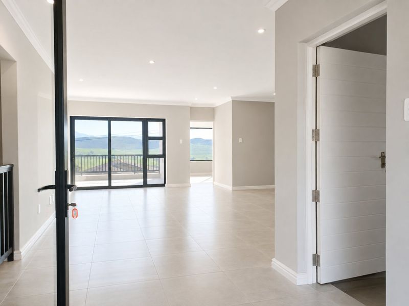 Spacious, modern open-plan living area featuring neutral tiled floors, recessed lighting, and large sliding doors leading to a balcony with scenic views.