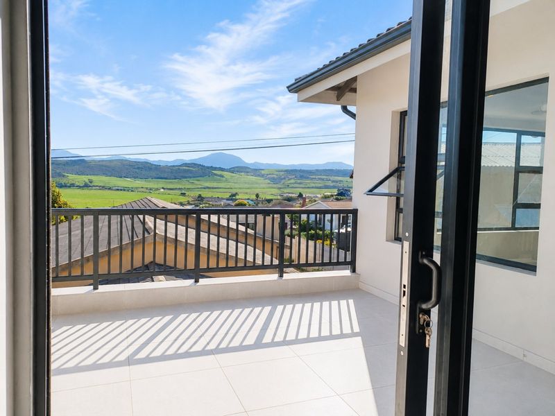 A clean, modern balcony featuring tiled flooring and a metal balustrade, offering expansive views of the surrounding landscape.