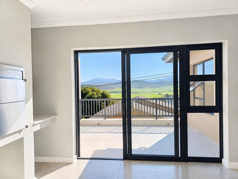 Bright living area featuring a built-in fireplace, modern tiled floors, and large sliding doors opening onto a balcony with scenic mountain views.