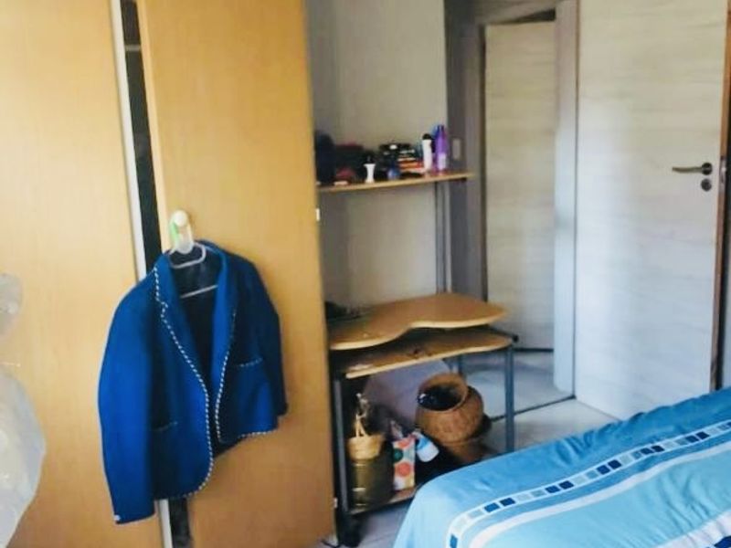 A bedroom featuring tiled flooring, built-in wardrobe storage, and textured ceiling tiles, offering a functional space with potential for cosmetic updates.