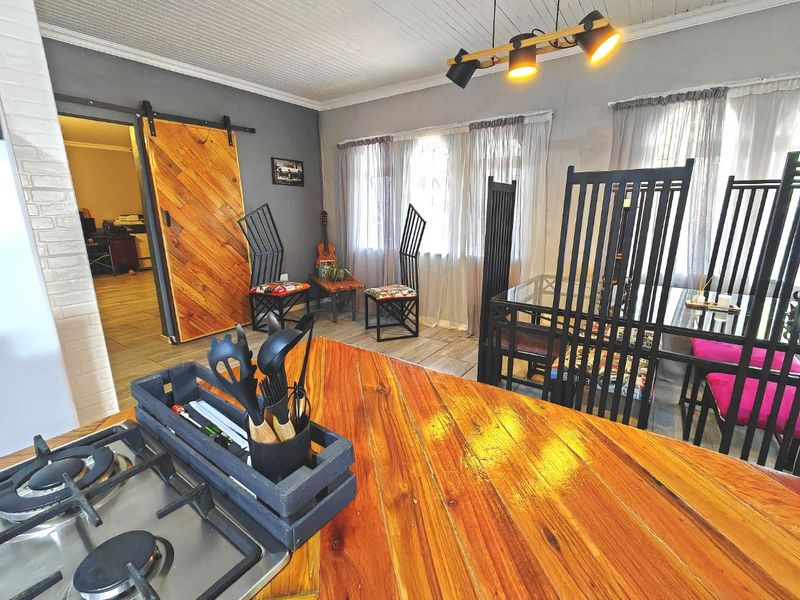 Open plan living and dining area featuring a timber countertop kitchen island with integrated gas hob and a distinctive sliding barn door.