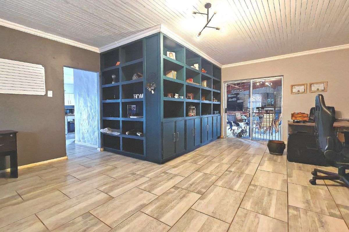 Spacious living area featuring wood-look tiled flooring, a prominent built-in dark blue shelving unit, and direct access to an outdoor patio through sliding doors.