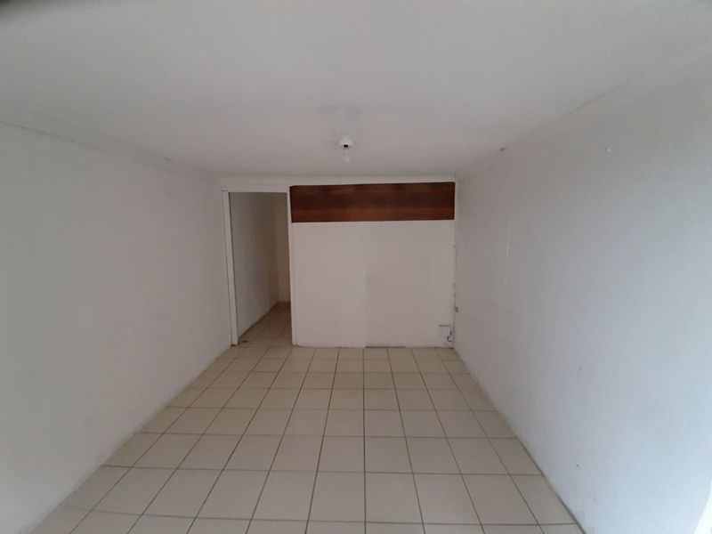 An empty, functional utility space featuring neutral tiled flooring and a simple ceiling light fixture, suitable for various industrial or storage purposes.