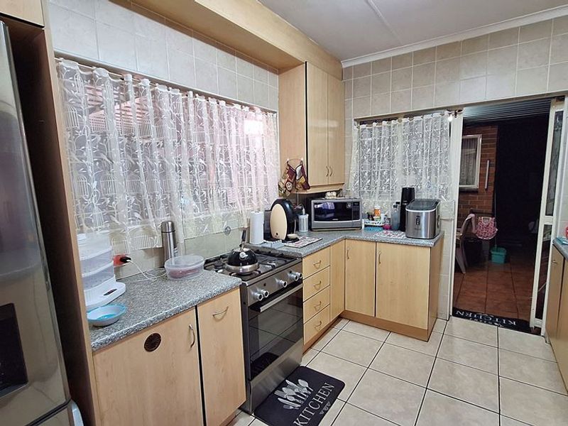 A functional kitchen featuring laminate cabinetry, granite countertops, a gas stove, and tiled finishes, offering a practical layout for daily meal preparation.