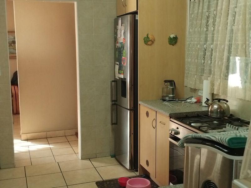 A functional kitchen featuring built-in cabinetry, gas hob, oven, and tiled finishes, providing a practical workspace with direct access to the adjacent hallway.