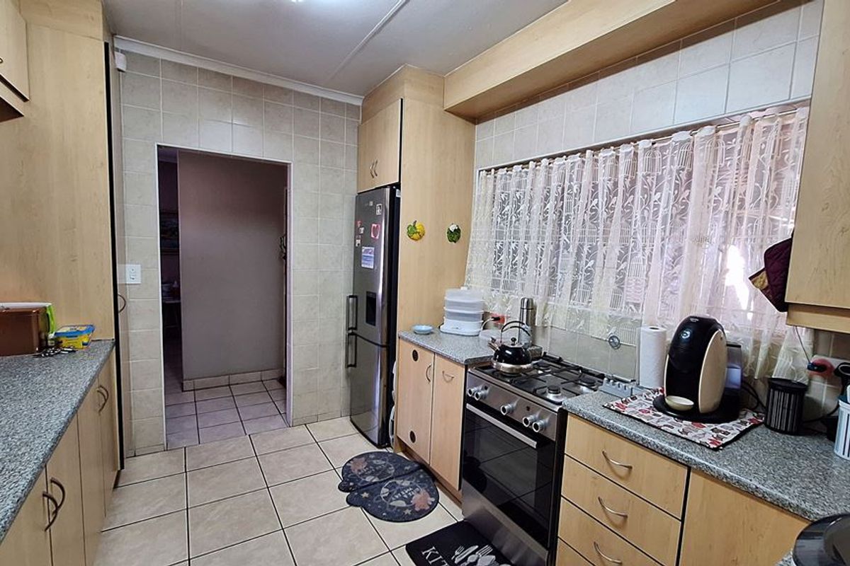A functional kitchen featuring laminate cabinetry, granite countertops, a gas stove, and tiled finishes throughout, offering a practical layout for daily meal preparation.