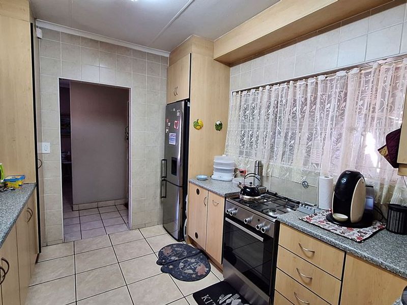 A functional kitchen featuring laminate cabinetry, granite countertops, a gas stove, and tiled finishes throughout, offering a practical layout for daily meal preparation.