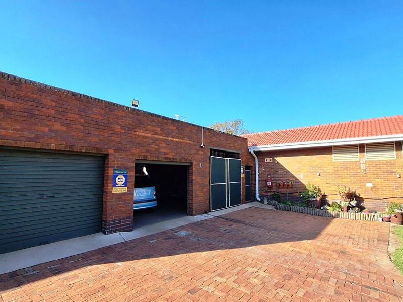 Front exterior view of the property featuring a brick facade, paved driveway, and a secure garage entrance.