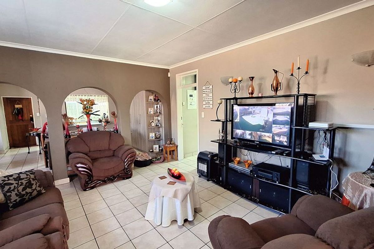 Spacious living room featuring tiled flooring, distinctive arched architectural dividers, and built-in shelving, offering a functional layout with neutral wall tones.