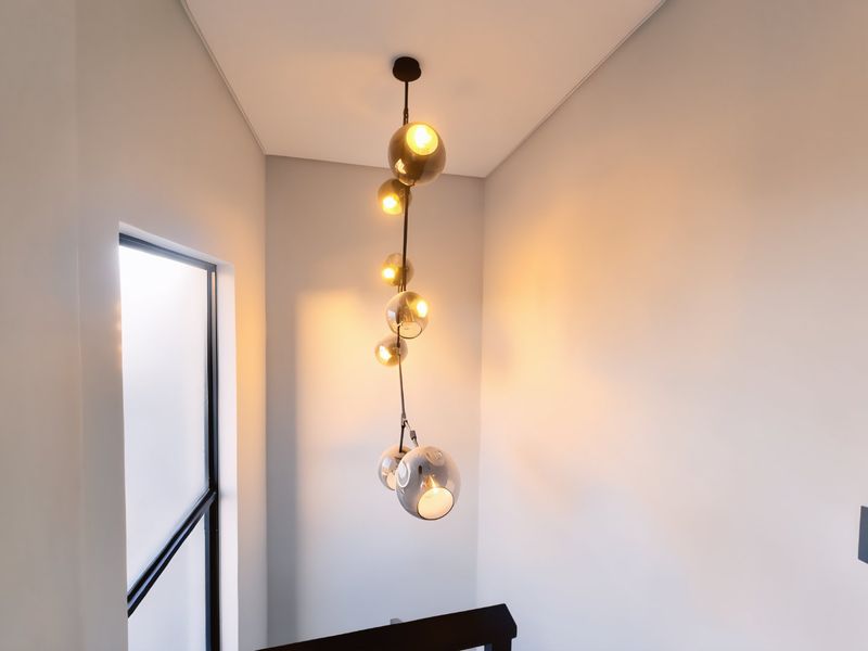 A modern hallway space featuring a contemporary multi-globe pendant light fixture and a sleek window with a dark frame.