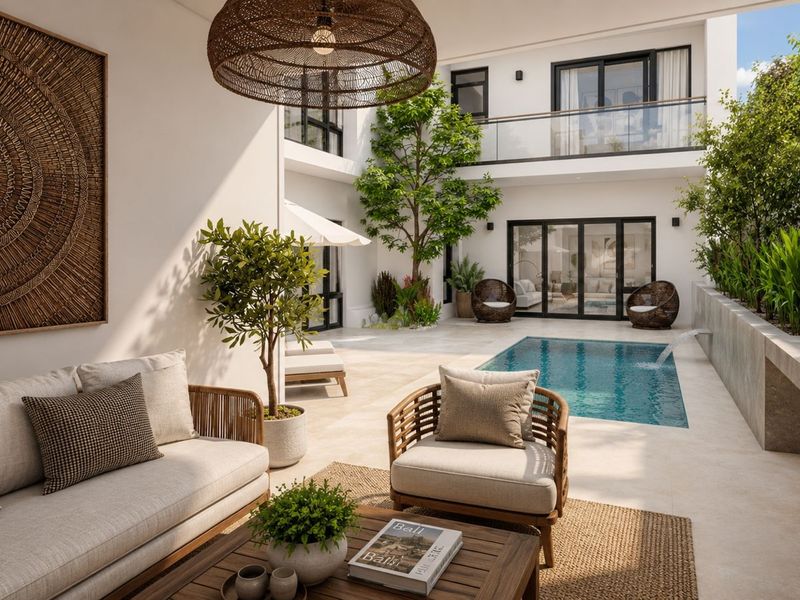 A modern, luxurious courtyard featuring a private swimming pool, stone patio, and seamless indoor-outdoor flow through large sliding glass doors.
