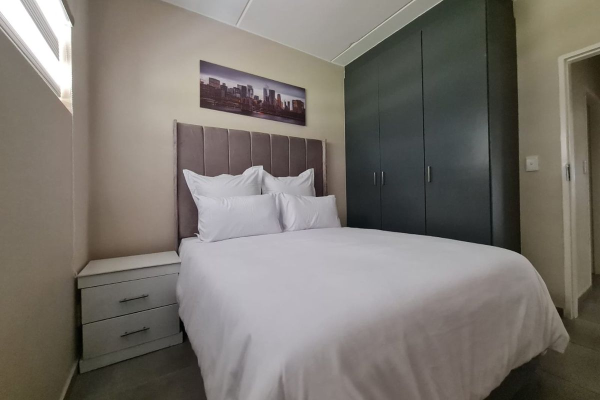 A well-maintained bedroom featuring dark built-in cupboards and neutral wall finishes, providing a clean and functional sleeping space.